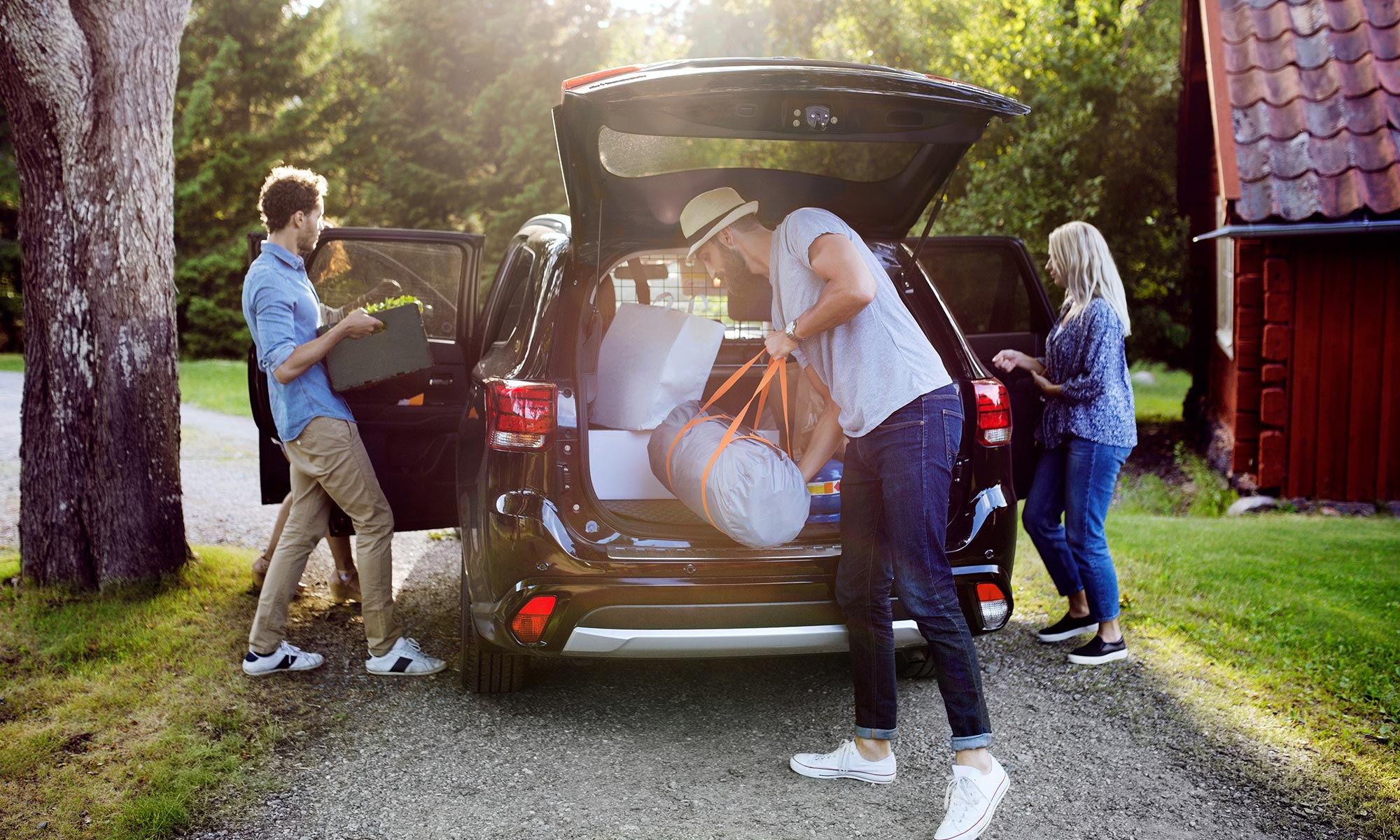 Tre unga vänner packar ur en bil vid en sommarstuga