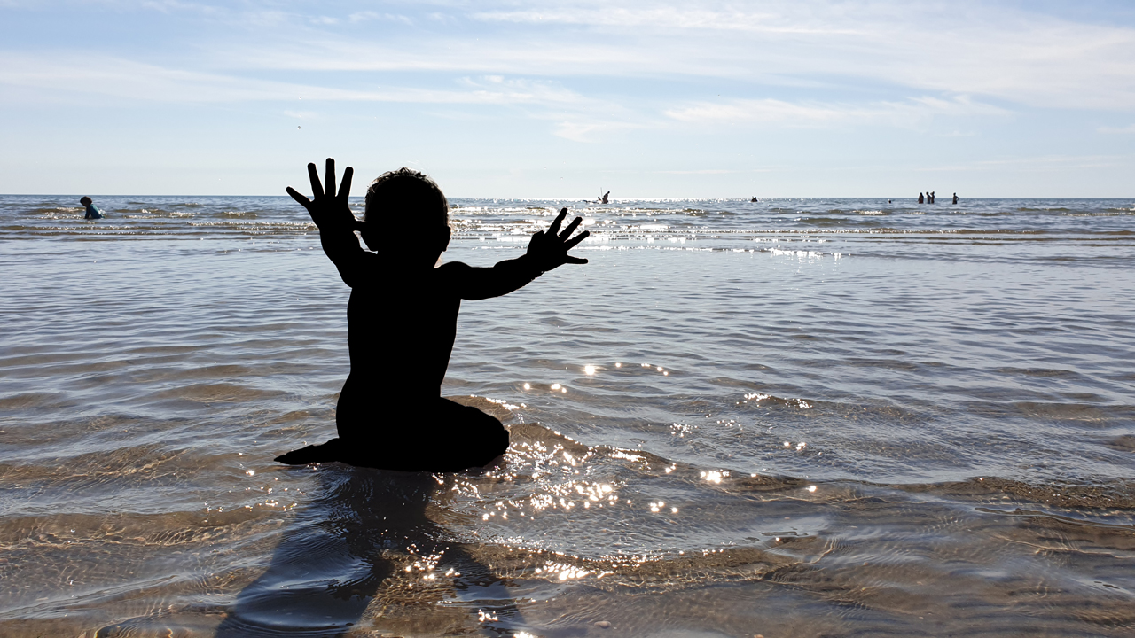 Child playing in the water close to the beach