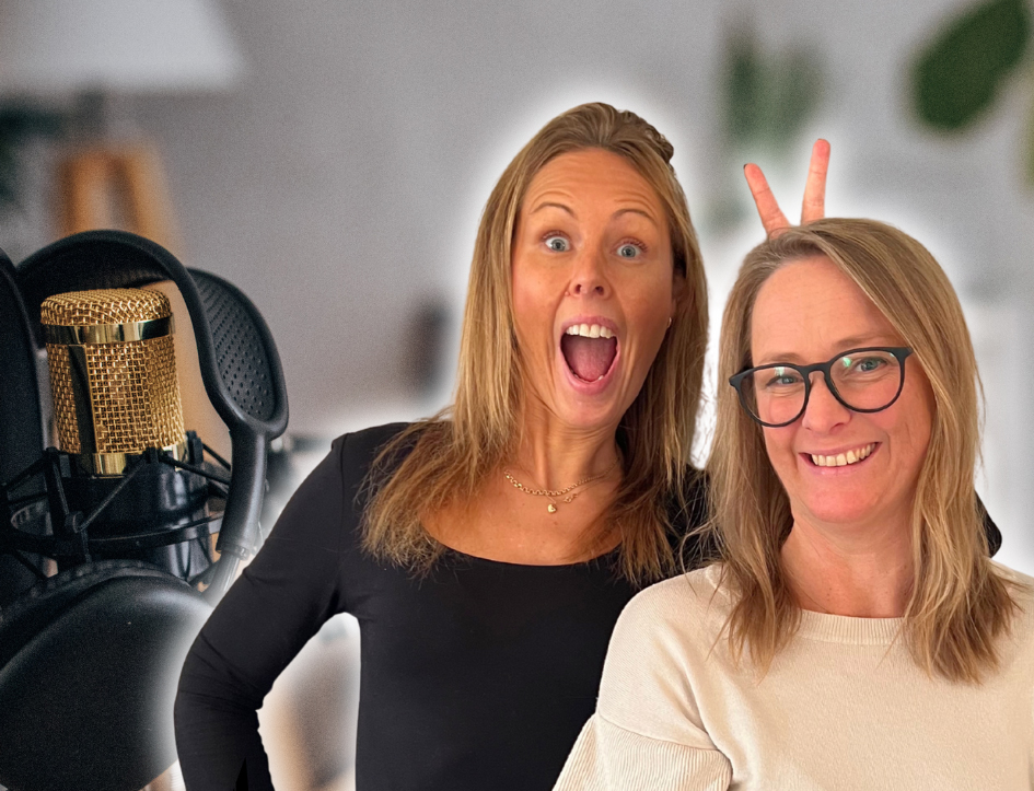 Två leende kvinnor står framför en mikrofon, där den ena skämtsamt gör kaninöron bakom den andra.
