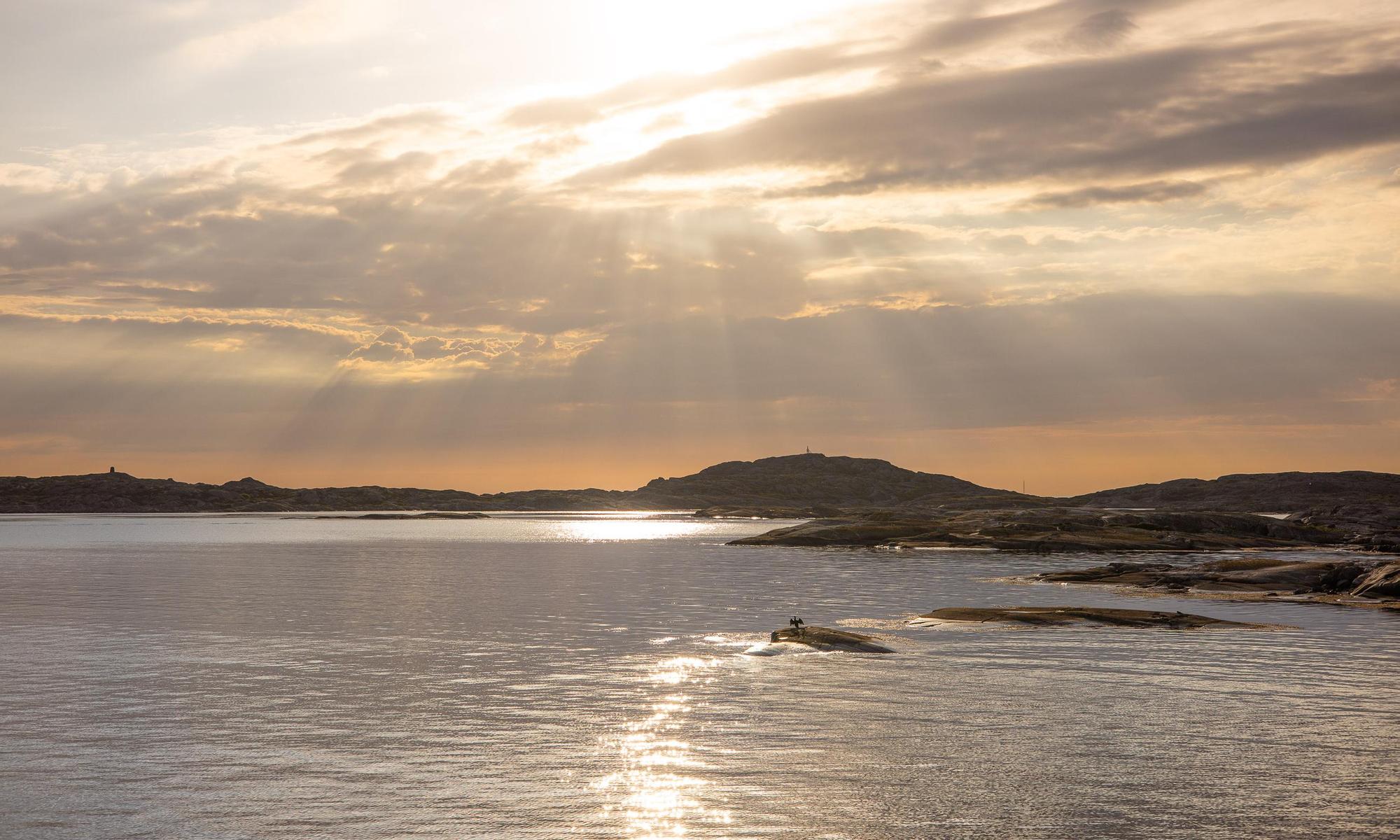 Solen bryter igenom molnen vid bohuslänska klippöar